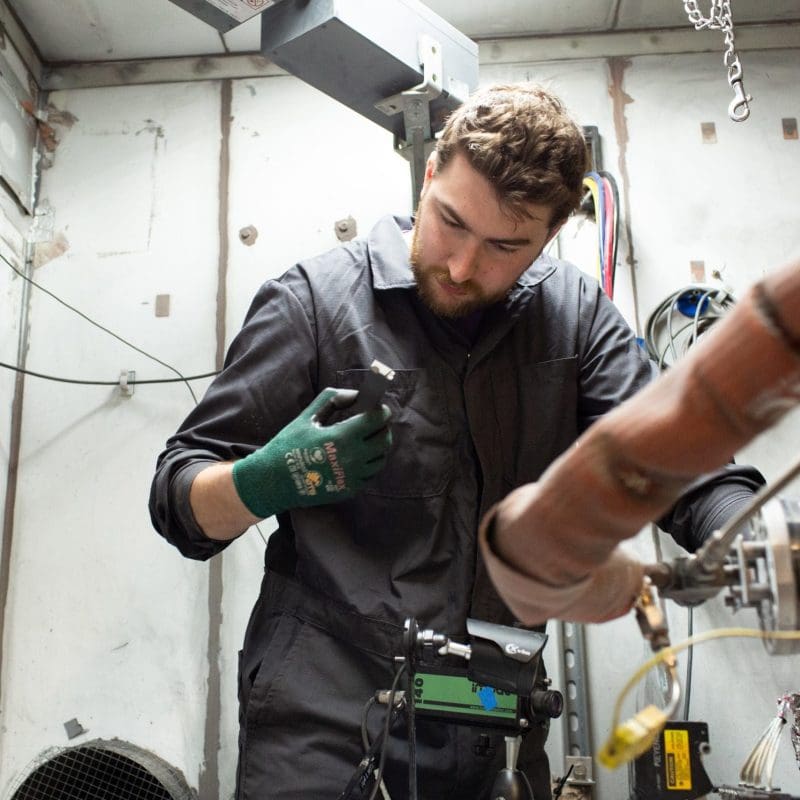 A man working in a machine in a cold spray lab