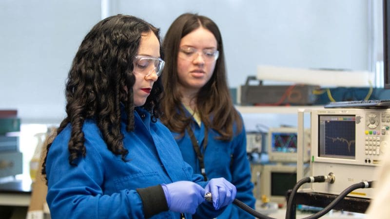 One woman showing another woman how to use a piece of equipment in the Materials and Devices lab
