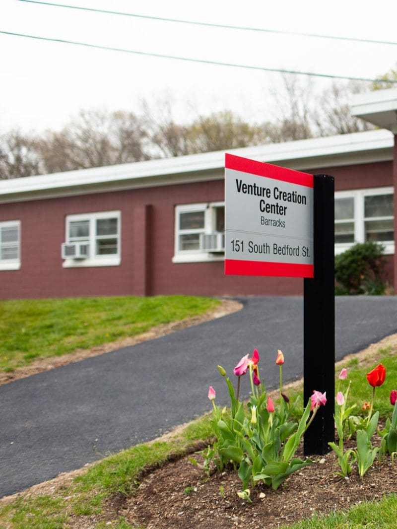 Venture Creation Center signage out in front of the building with green grass and tulips
