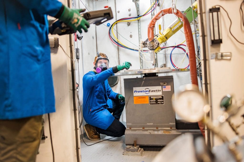 Two men suited up working in the Cold Spray lab